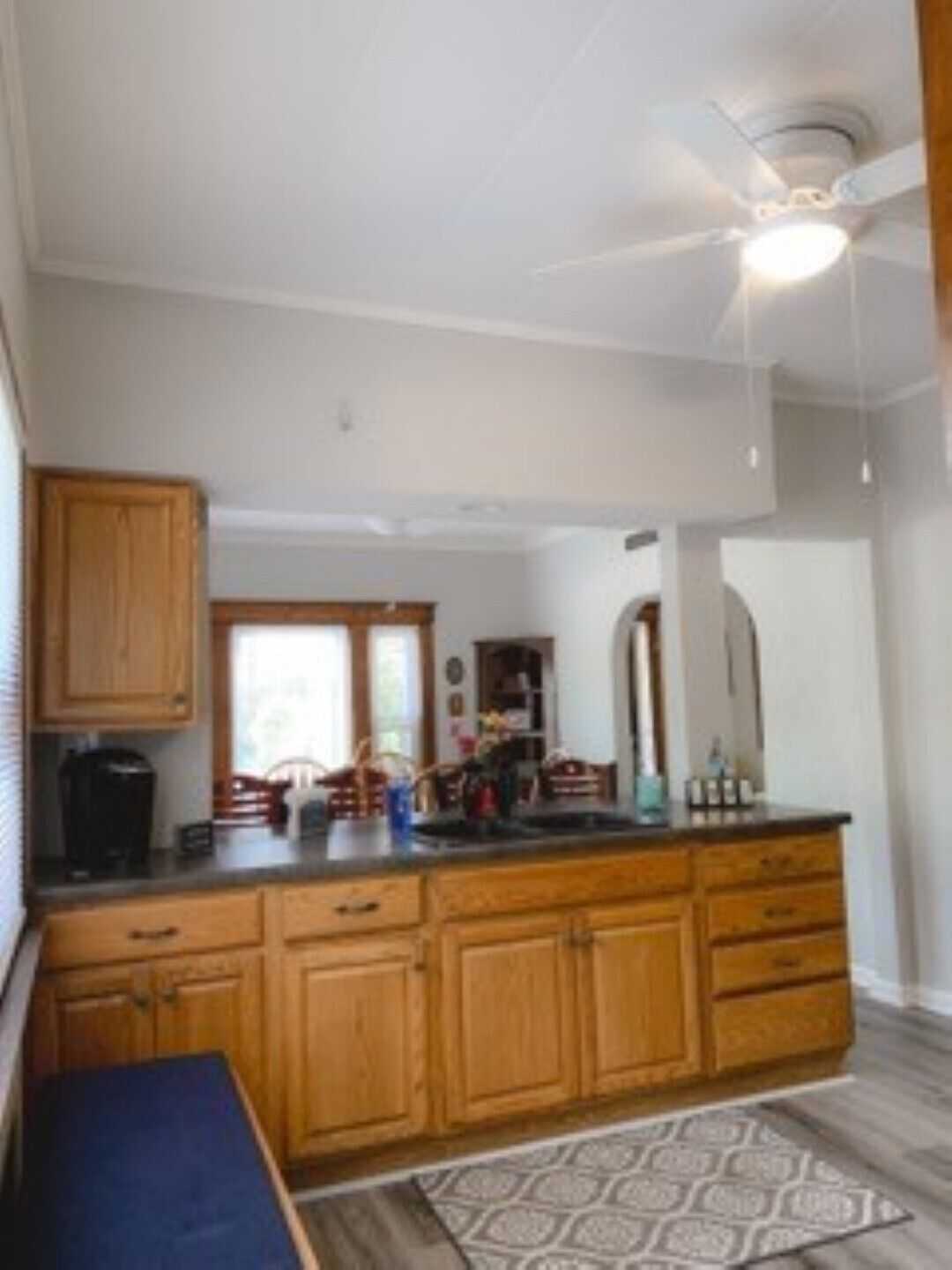 A kitchen with wooden cabinets, a black countertop, and a ceiling fan.