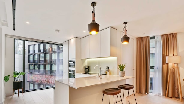 Une cuisine moderne dotée d’un îlot central, de tabourets de bar et de luminaires suspendus.