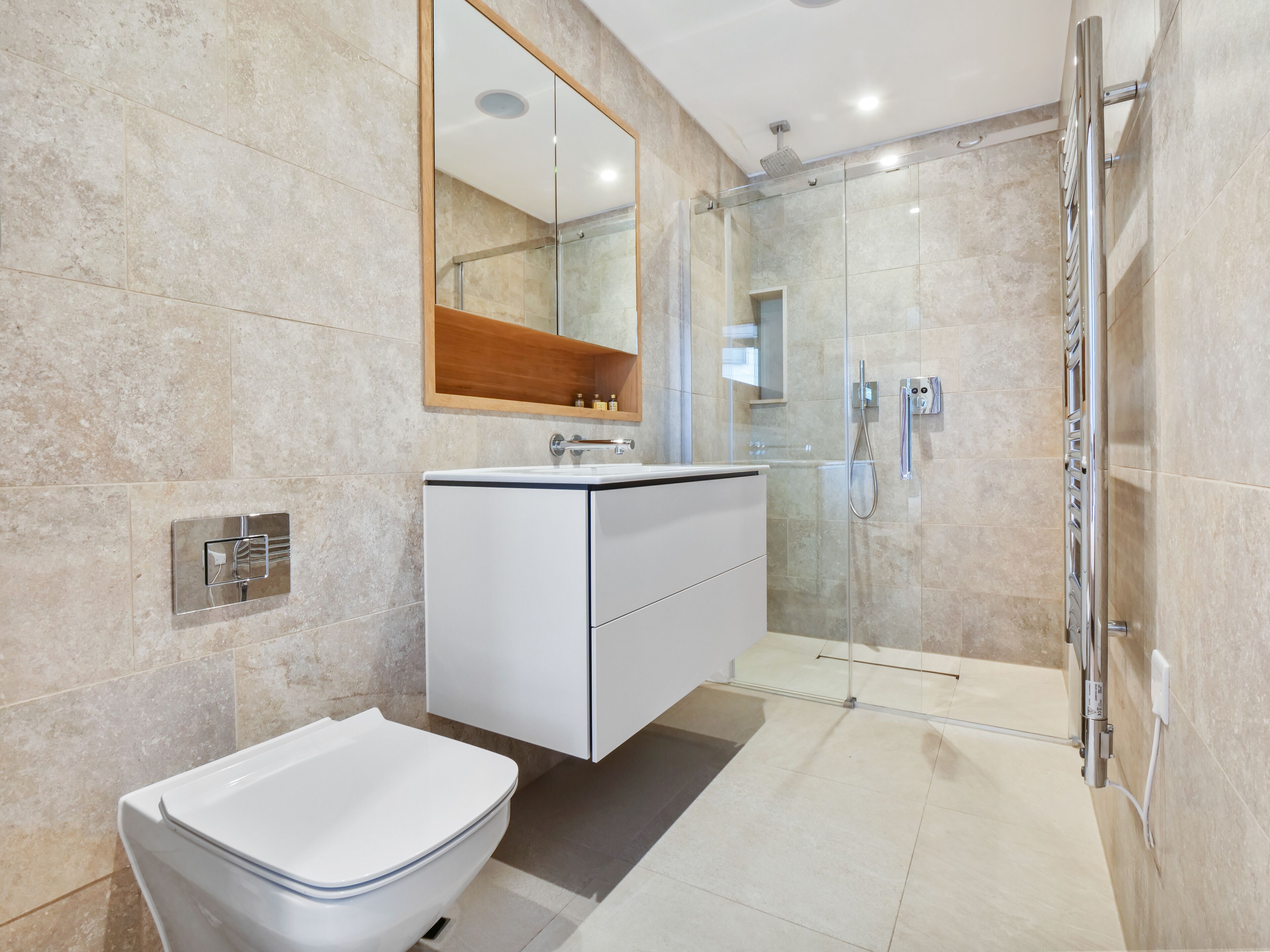 A modern bathroom with a glass shower enclosure, a white vanity, and a large mirror.