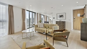 Un salon spacieux avec un canapé, des fauteuils, une table basse et un coin repas à l’arrière-plan.