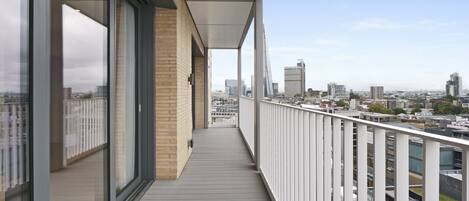 Ein moderner Balkon mit großen Fenstern und Blick auf die Stadt.