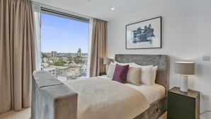 Une chambre d’hôtel moderne dotée d’un grand lit, offrant une vue sur la ville et présentant un décor minimaliste.