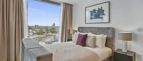 Una habitación de hotel moderna con una cama grande, vistas a la ciudad y una decoración minimalista.