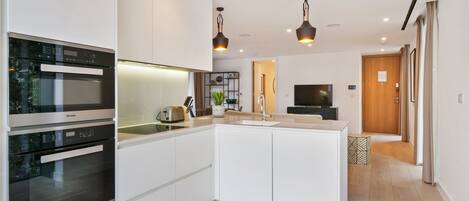 A modern kitchen with built-in appliances, a central island, and pendant lighting.