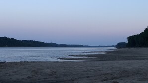 Een strand met een breed zandstrand en kalm water.