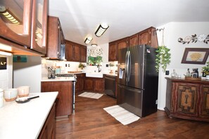 A kitchen with wooden cabinets, a stainless steel refrigerator, and a white countertop. - Tranquil Lake View Dome Home in Wine Country (Lower Lake)