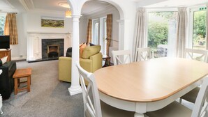 A spacious room with a fireplace, a dining table, and a sofa. - Bridgedown House (Richmond)