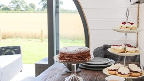 Ett matbord med ett kakfat, ett våningsfat för desserter och en mugg.