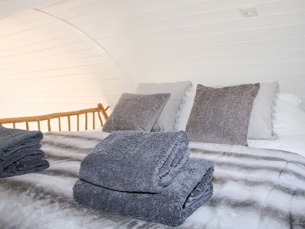 A neatly made bed with grey and white bedding, a wooden headboard, and a white ceiling. - Cherry Blossom (Craven Arms)