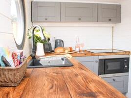 Cocina compacta con encimera de madera, un lavamanos, un tostador, una tetera, una hogaza de pan y una botella de vino.