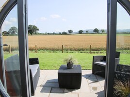 Un patio con mobiliario de mimbre y vista a un campo.