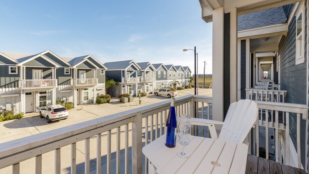 A row of beach houses with a balcony and a table with a bottle and glass. - 4br/3Ba Oceanview from balcony!  Sleeps 12 w/ hot tub! (Corpus Christi)