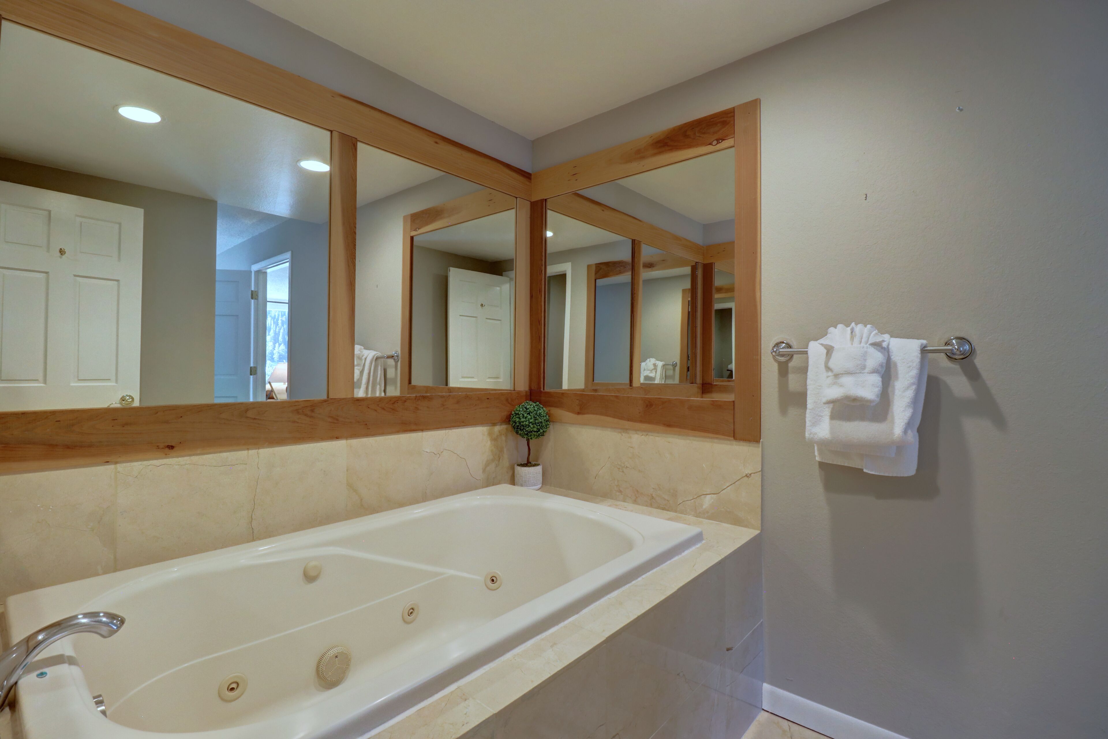 Ein Badezimmer mit einer großen Badewanne, Holzbalken, einem Spiegel und einem Handtuchhalter.