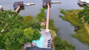 Propiedad frente al lago con piscina, muelle y terraza de madera.