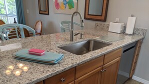 A kitchen with granite countertops, wooden cabinets, a stainless steel sink, and a dishwasher.