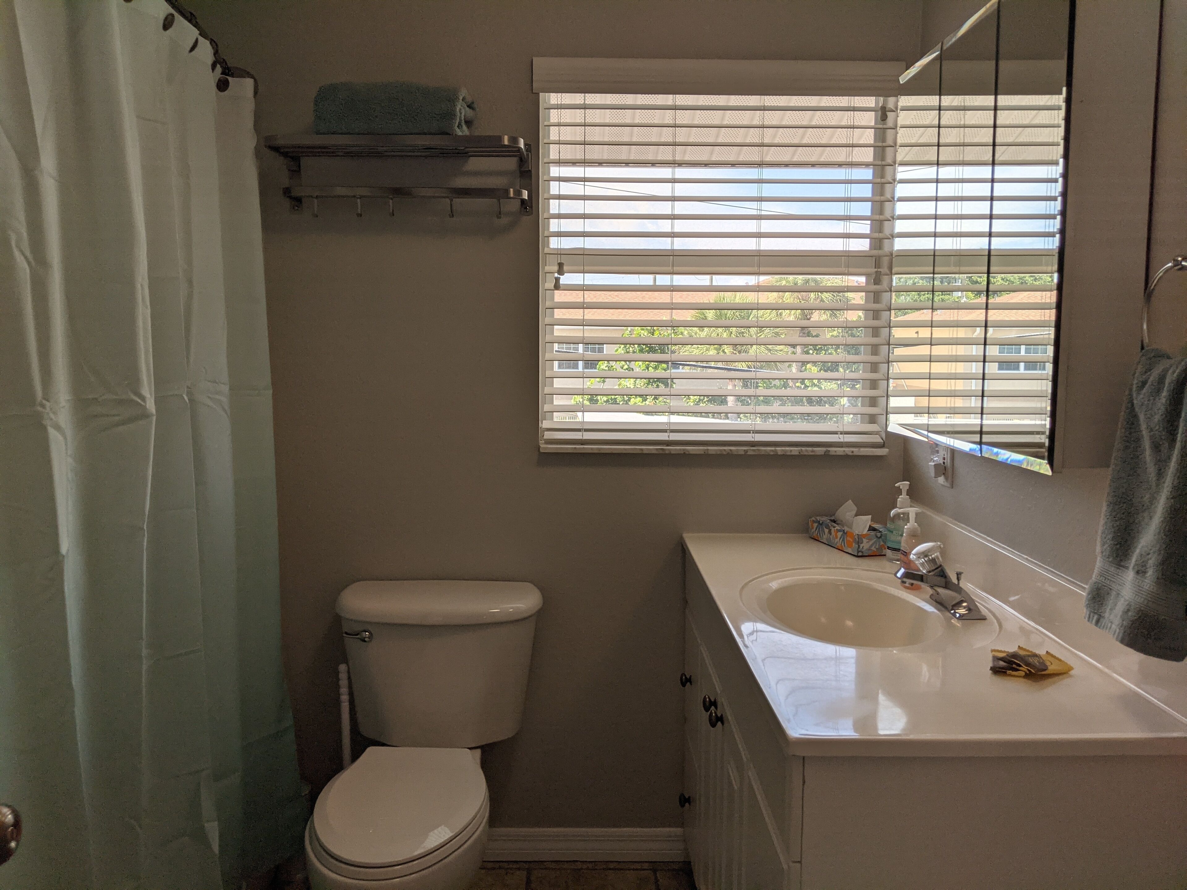Un baño con inodoro, lavamanos y ventana con persianas.