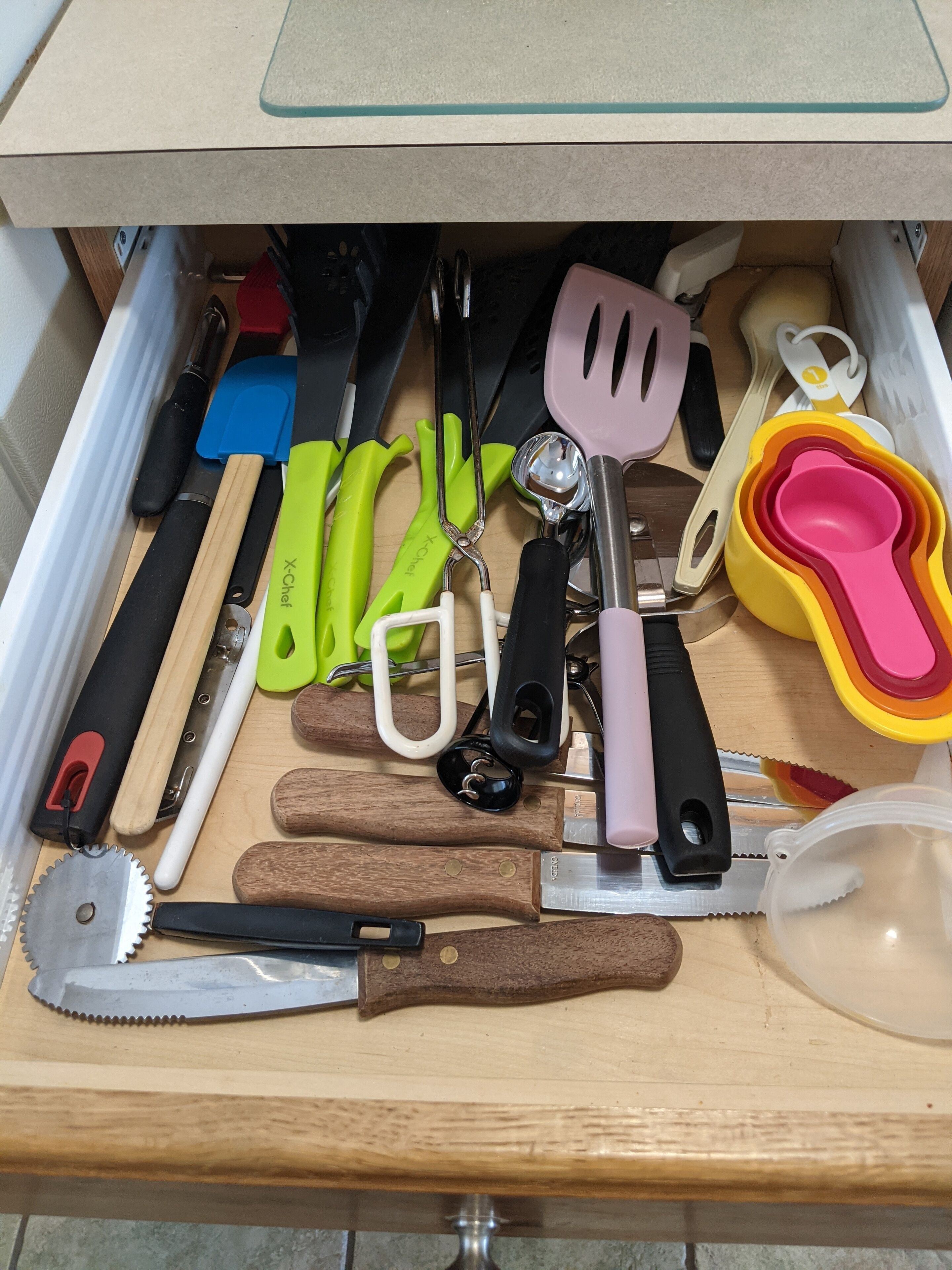 Een lade met verschillende keukengerei, zoals messen, spatels en maatbekers.