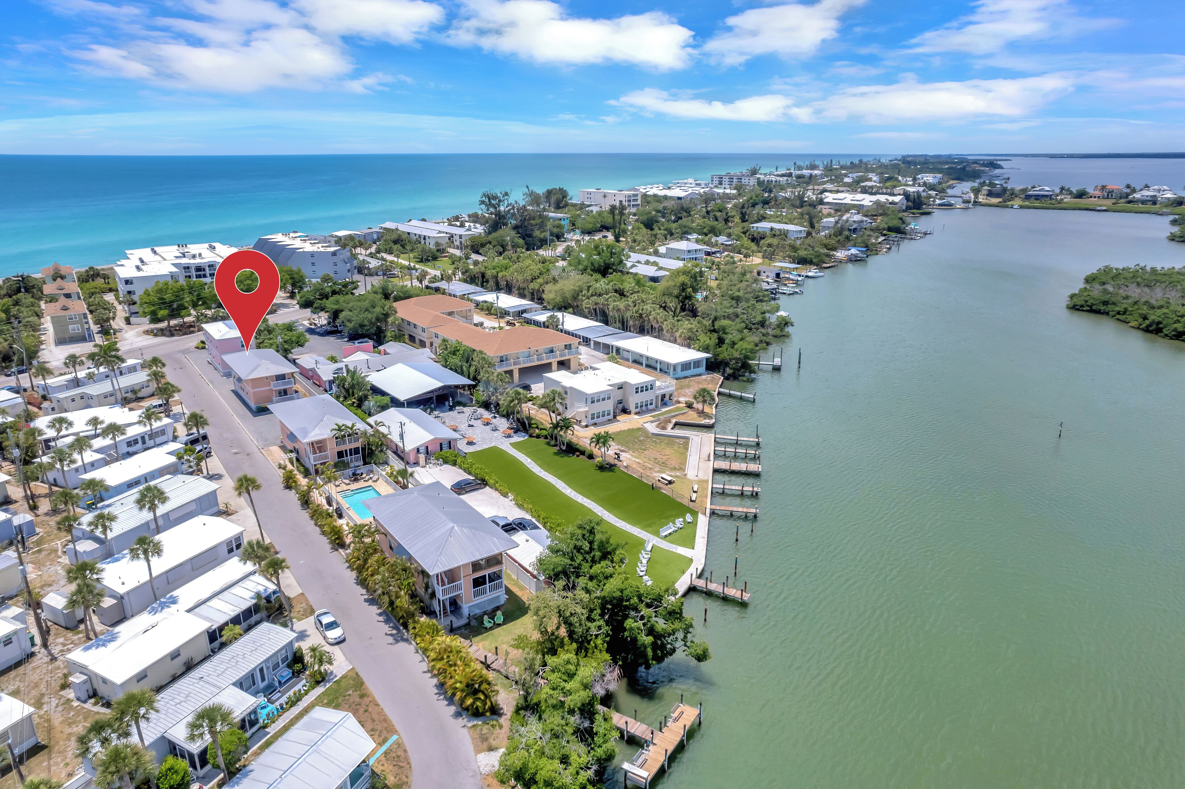 An aerial view of a coastal residential area with houses, a swimming pool, and a marina.
