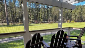 A covered outdoor seating area with wooden chairs and a view of a golf course. - Cozy Condo on the 4th Fairway of  Plumas Pines Golf Course (Blairsden Graeagle)