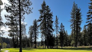 A well-maintained golf course with a clear path, surrounded by tall pine trees and a clear blue sky. - Cozy Condo on the 4th Fairway of  Plumas Pines Golf Course (Blairsden Graeagle)