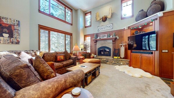 A spacious living room with a fireplace, leather sofas, and a television.