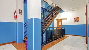 Una escalera con barandillas azules y escalones de madera que conduce a un rellano con una puerta marcada 'WATER'.
