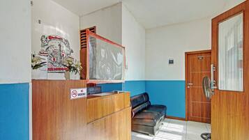 A reception area with a wooden desk, a blue wall, a black leather couch, and a door marked "101".