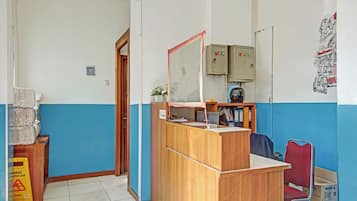 Ein Empfangsbereich mit einem Holztisch, einem Spiegel und einer blauen und weißen Wand. Es gibt Schränke, eine Tür und ein Plakat an der Wand.