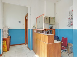 Una zona de recepción con un escritorio de madera, un espejo y una pared azul y blanca. Hay armarios, una puerta y un cartel en la pared.