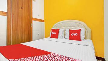 A hotel room with a bed, a wooden door, and a yellow wall.