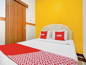 Una habitación de hotel con una cama, una puerta de madera y una pared amarilla.