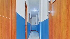 Un pasillo con puertas de madera y paredes azules que conduce a una habitación con piso de baldosas.