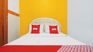 Una cama con cabecera blanca, dos almohadas con la marca 'OYO' y una colcha de cuadros rojos y blancos.