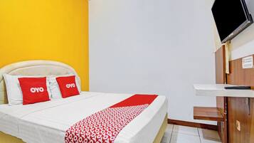 Ett hotellrum med en säng, en tv och ett skrivbord i trä.