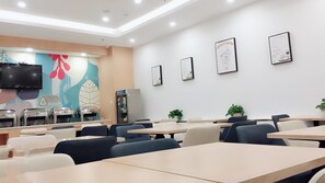 Un comedor con mesas y sillas, un televisor y decoración en la pared.