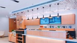 A modern reception area with a counter, digital display, and pendant lighting. - Hanting Hotel Shanghai Waigaoqiao Free Trade Zone (Shanghai)
