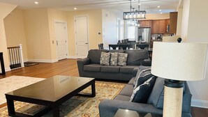 A living room with a sofa, coffee table, and lamp. There is a staircase leading to another room. - BEACHBLOCK FIRST HOUSE FROM BEACH WITH POOL OCEANVIEW 4 DECKS NEAR BOARDWALK (North Wildwood)