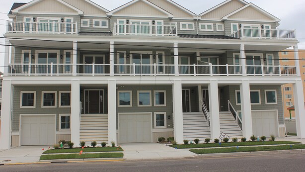 A multi-story residential building with a front porch, two balconies, and a staircase leading to the upper floor. - BEACHBLOCK FIRST HOUSE FROM BEACH WITH POOL OCEANVIEW 4 DECKS NEAR BOARDWALK (North Wildwood)