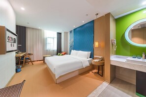 A hotel room with a bed, bedside table, lamp, and a bathroom with a sink and mirror. - Ji Hotel (Xiamen)