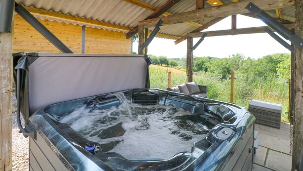 A hot tub under a wooden pergola with a view of greenery. - Bowland Barn (Lancaster)