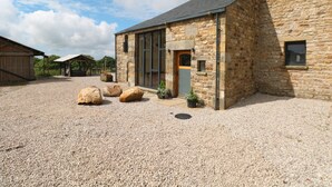 A stone building with a gravel driveway and large rocks. - Bowland Barn (Lancaster)