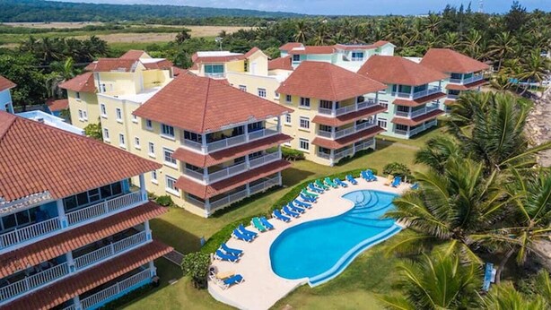 Een resort met meerdere gebouwen, een zwembad en uitzicht op het strand.