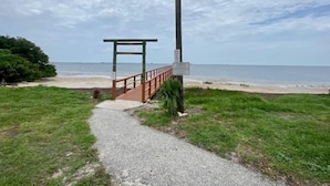 A pathway leading to a beach with a wooden structure and a signpost. - Cozy 2 BR Home, walking distance to Crystal Beach/Park - Quaint Family Getaway! (Palm Harbor)