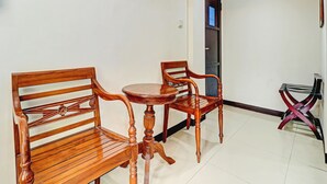Un coin repas avec des chaises en bois et une table, une porte en arrière-plan, et une petite table avec un cadre en métal.