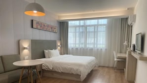 Una habitación de hotel con cama, sofá, escritorio y una silla.