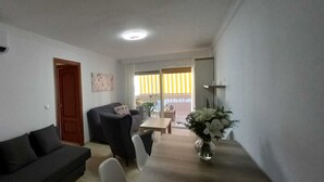 A living room with a sofa, a dining table, and a vase of flowers. - 3 bedroom apartment in San Luis de Sabinillas (San Luis de Sabinillas)
