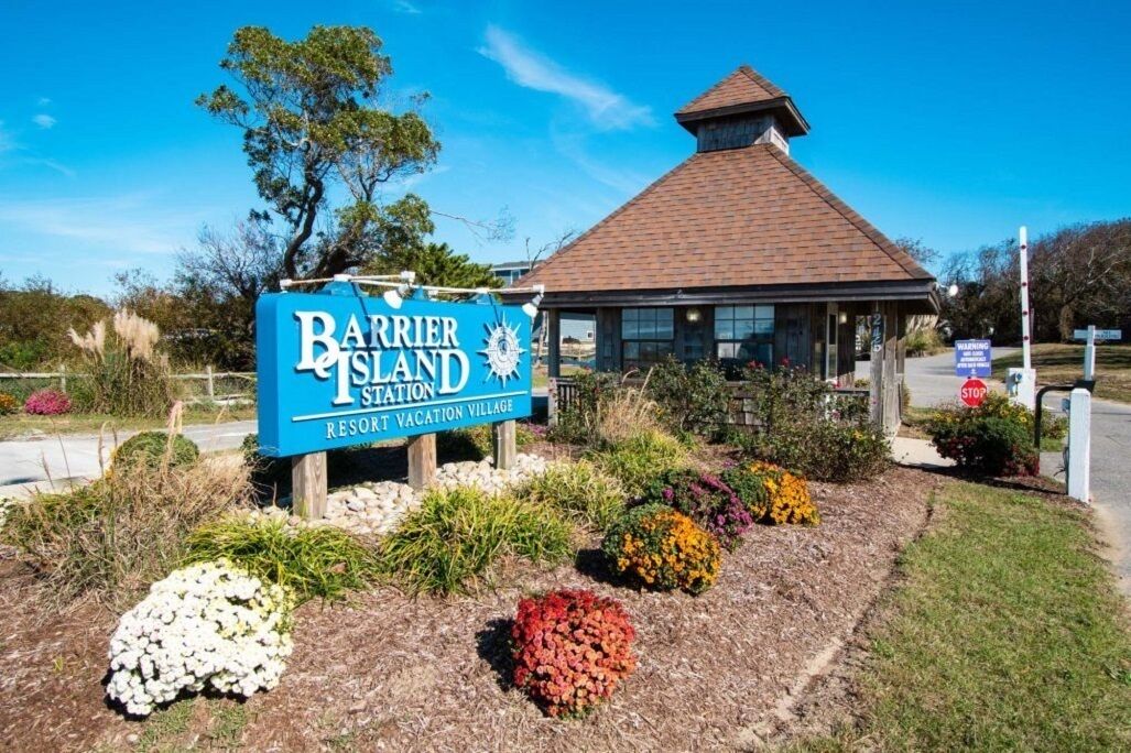 Une enseigne indiquant le complexe hôtelier « Barrier Island Resort Vacation Village », avec un petit bâtiment en arrière-plan.