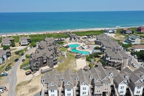 Uma área residencial costeira com várias casas, uma piscina e uma praia ao fundo.
