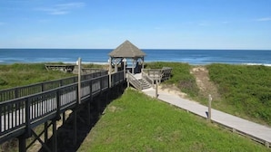 A wooden boardwalk leading to a gazebo by the beach.