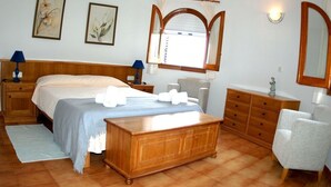 A bedroom with a bed, bedside tables, a dresser, a chair, and a window with curtains.
